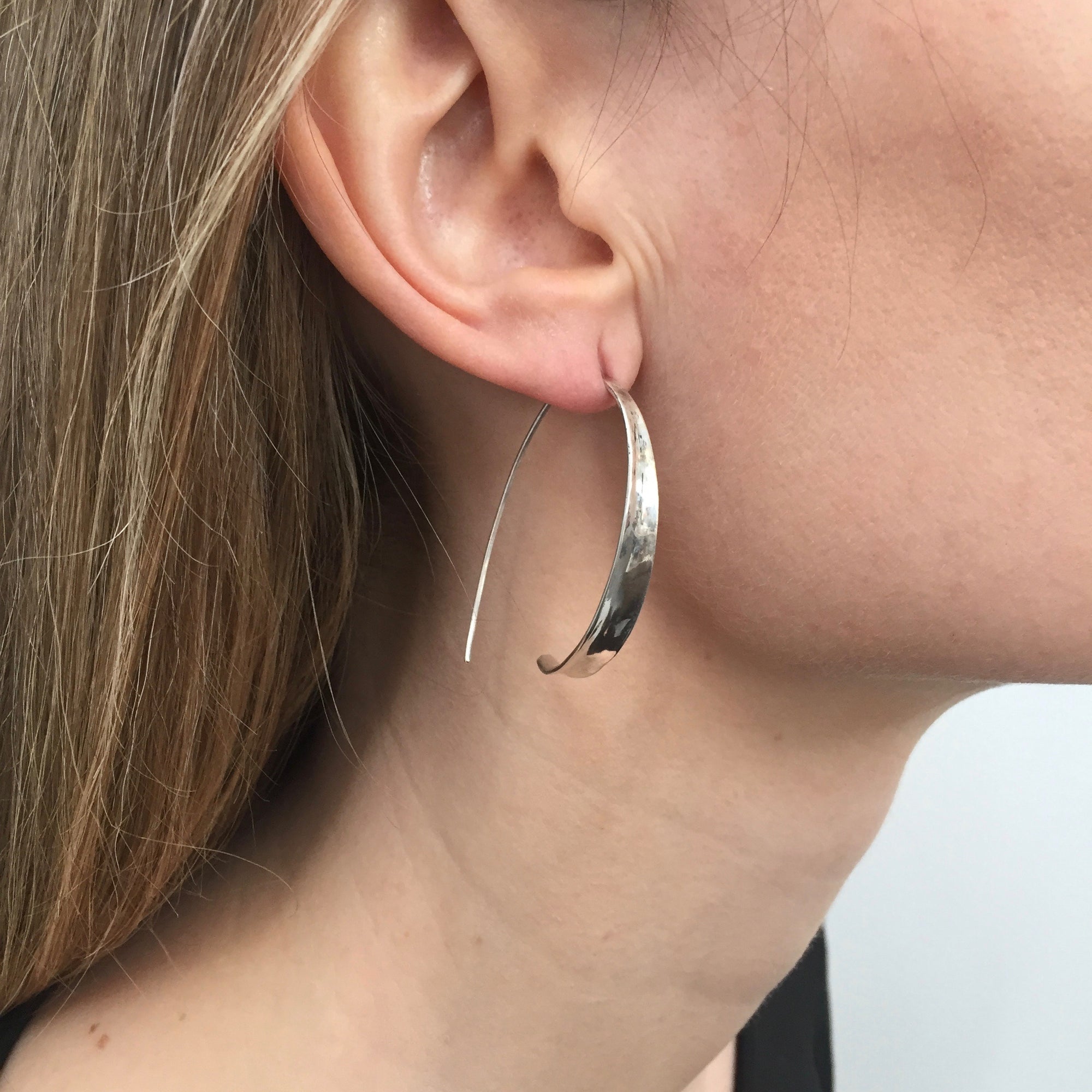 Minimal silver loop earrings being worn by model.