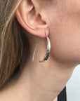 Minimal silver loop earrings being worn by model.