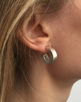 Chunky silver hoop earrings being worn by model.